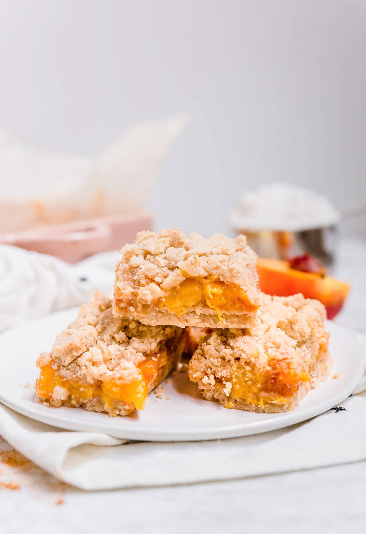 A view of three peach crumb bars in a stack on a plate.