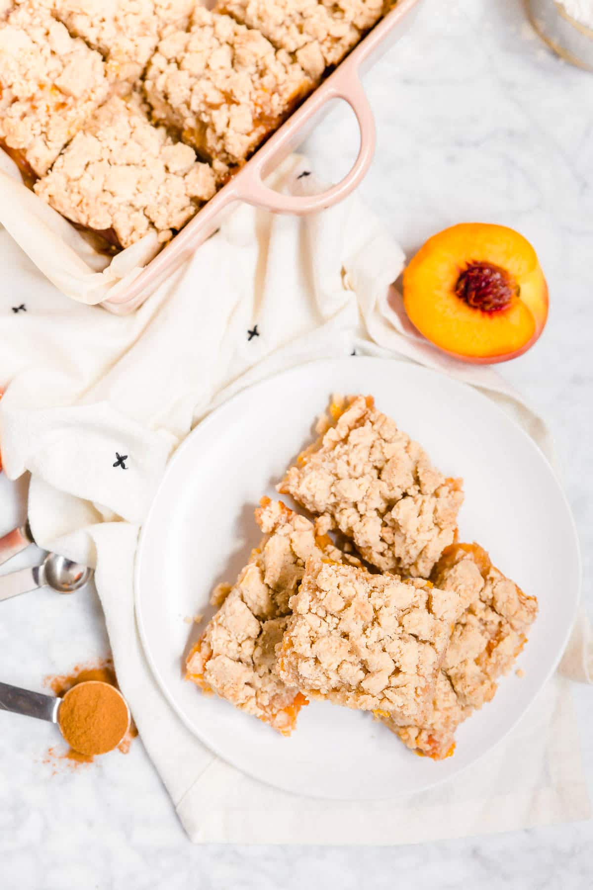 An aerial view of peach crumb bars on a plate with fresh peaches next to it.