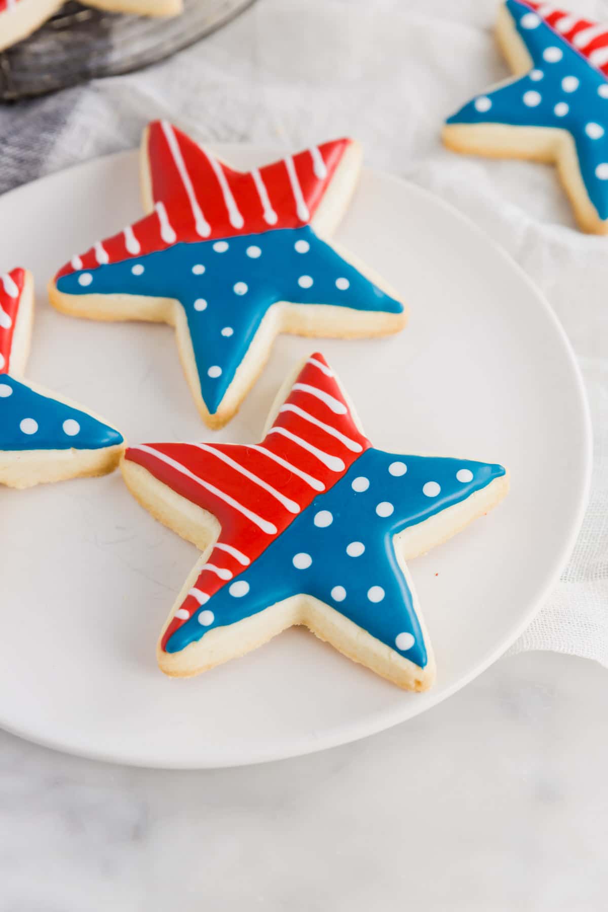 An aerial photo of a white plate with star shaped sugar cookies with a flag design on them.