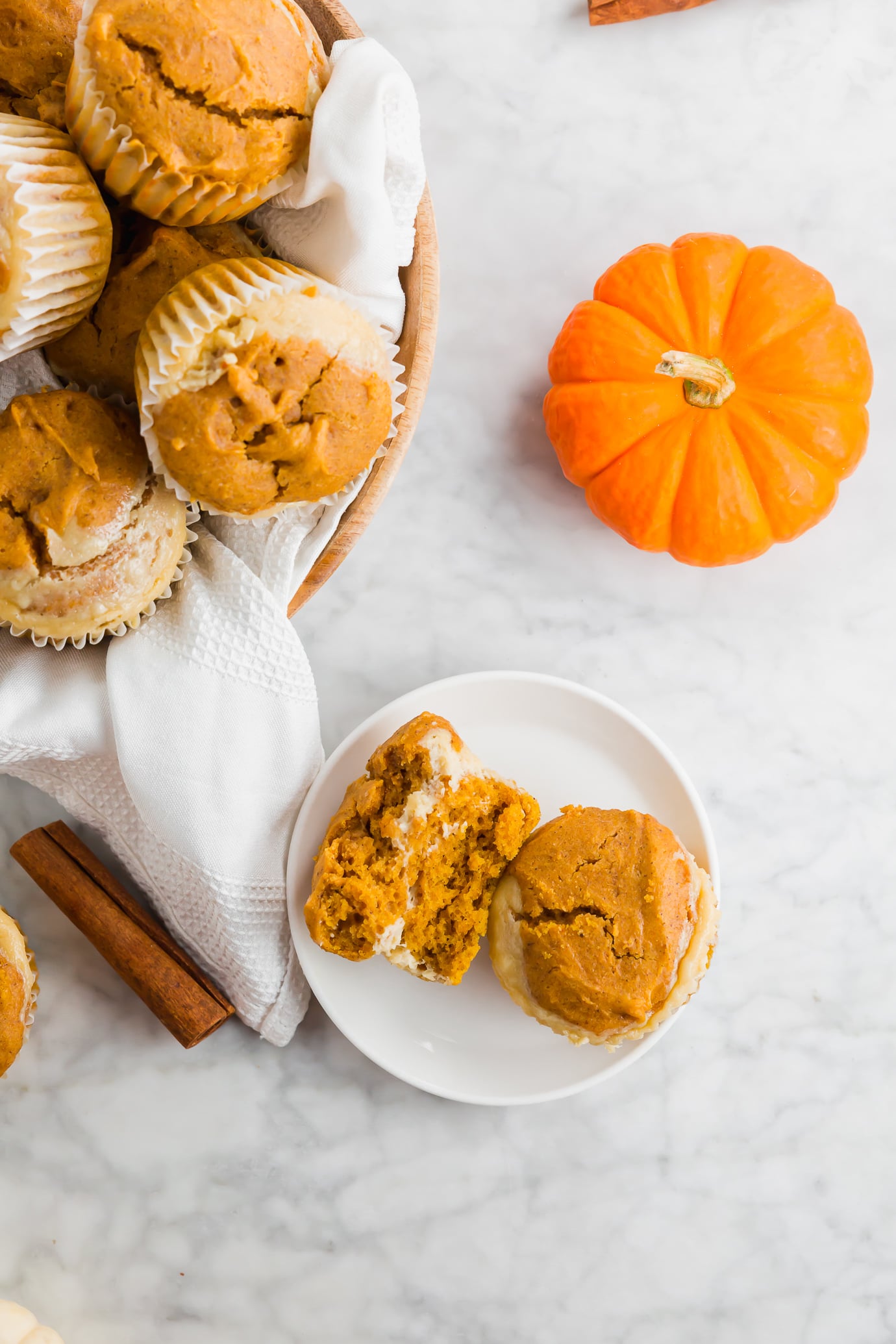 A photo of a pumpkin cheesecake muffin split in half on a plate.