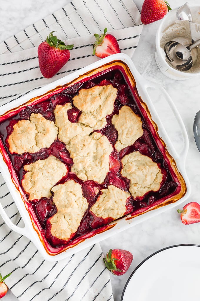 A photo of a baking dish with gluten free strawberry cobbler with vegan biscuits on top.