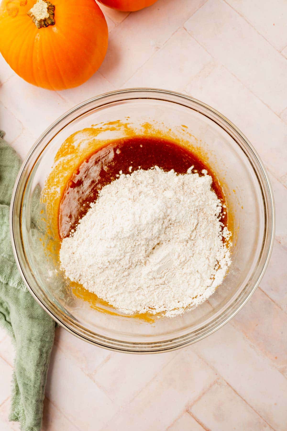 A glass mixing bowl with a brown sugar and butter mixture topped with a gluten-free flour blend.