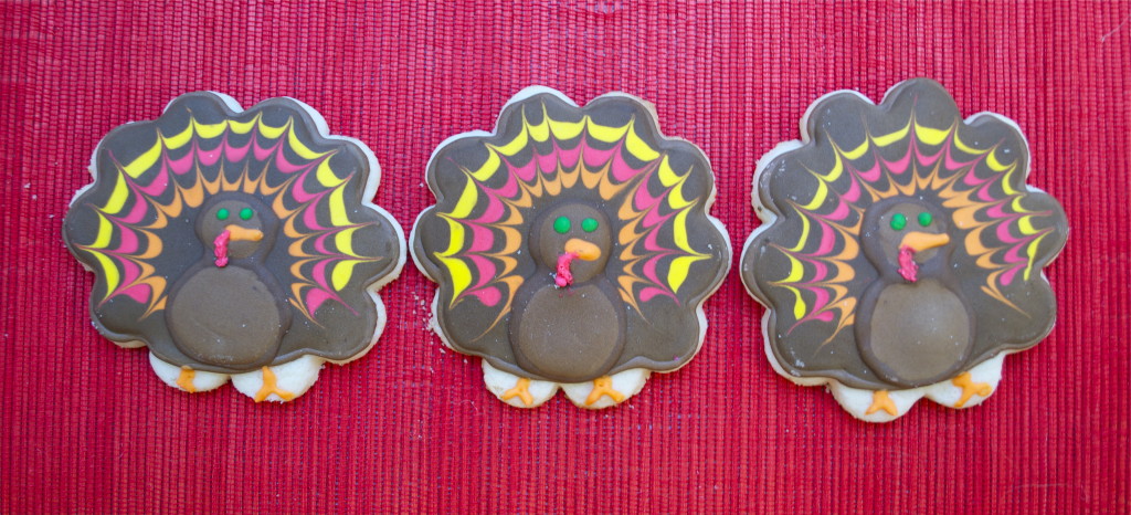 Three gluten-free turkey decorated sugar cookies on a red placemat.