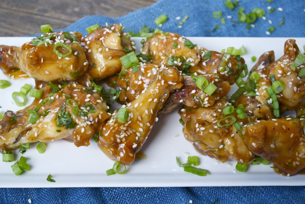 A platter of teriyaki chien wings topped with green onions and sesame seeds.