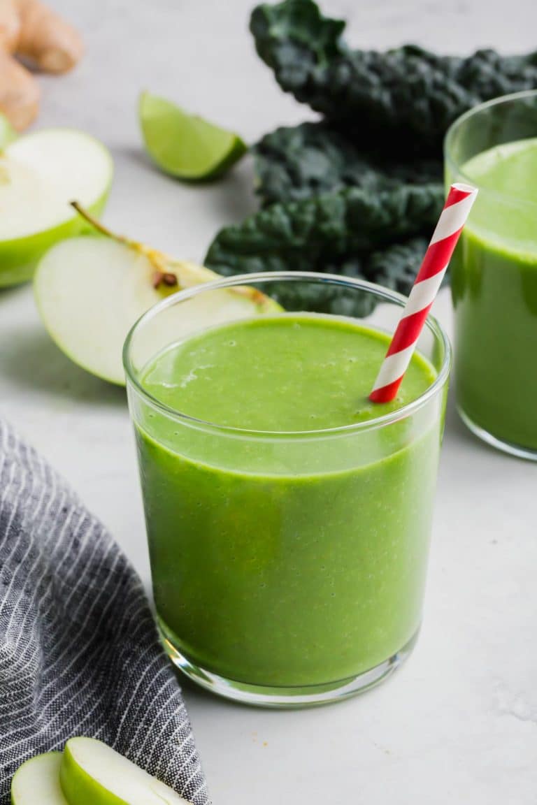 A glass of apple and kale smoothie with a straw.