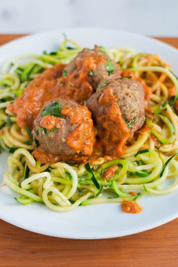 A plate of zoodles with turkey meatballs, topped with three juicy meatballs and covered in chunky red tomato sauce, served on a white dish.