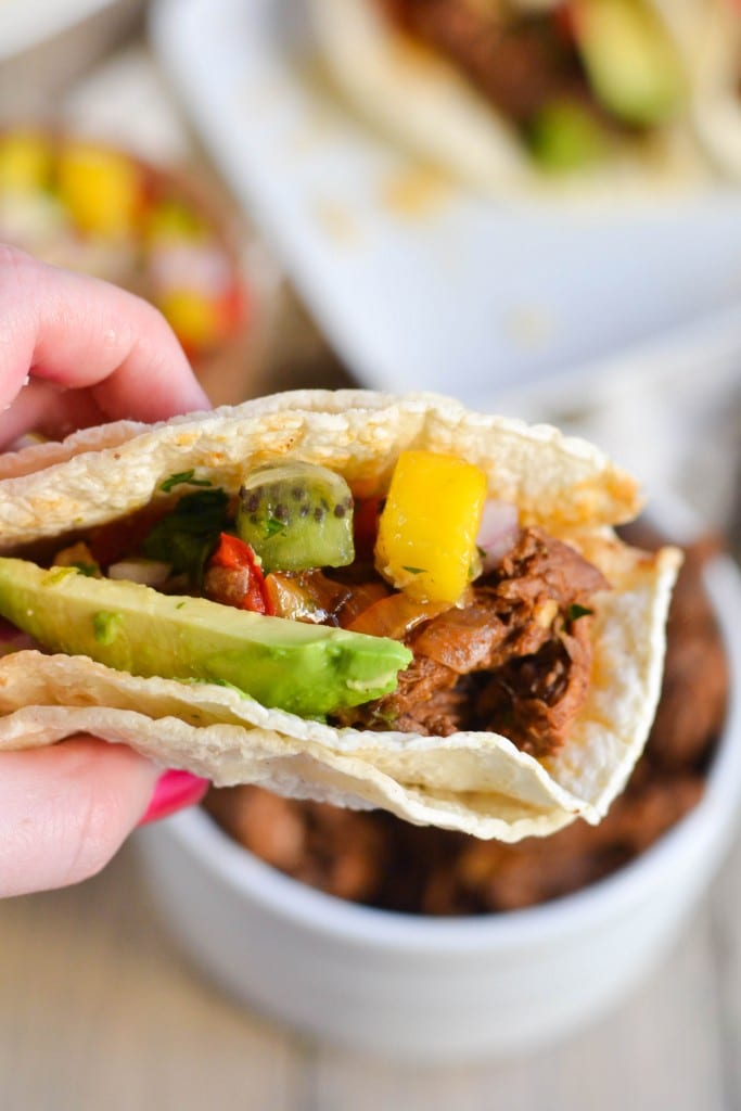 A hand holding a delicious Crockpot Shredded Beef Taco, ready to enjoy.