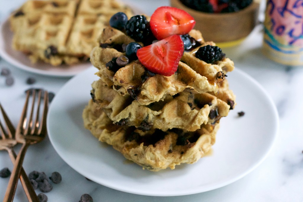 A stack of waffles topped with strawberries, blueberries and blackberries.