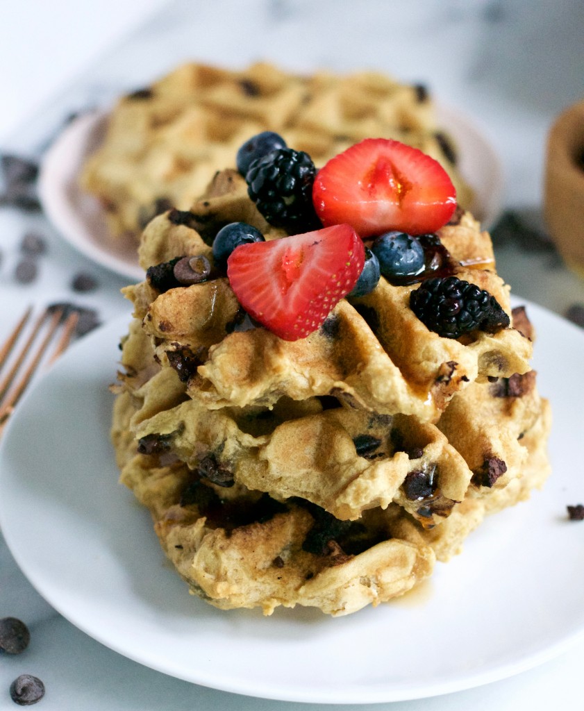 A stack of waffles topped with strawberries, blueberries, and blackberries.