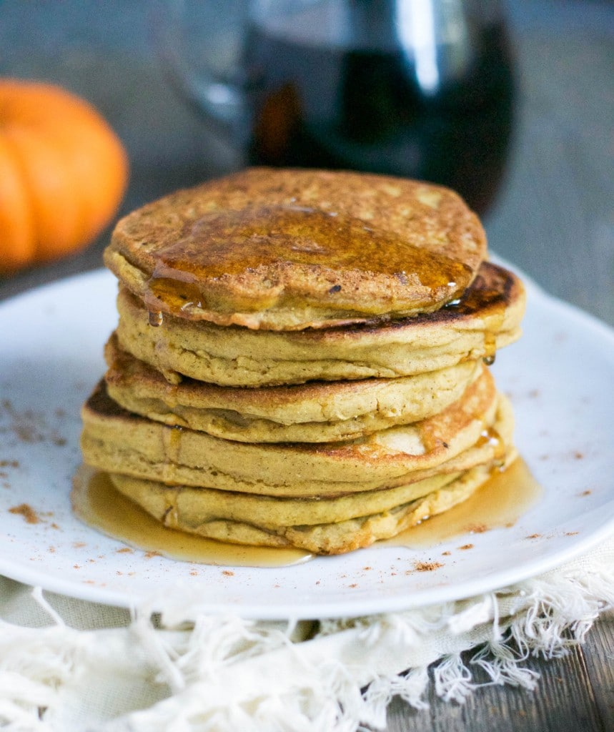 A stack of pumpkin pancakes with maple syrup dripping down the sides.