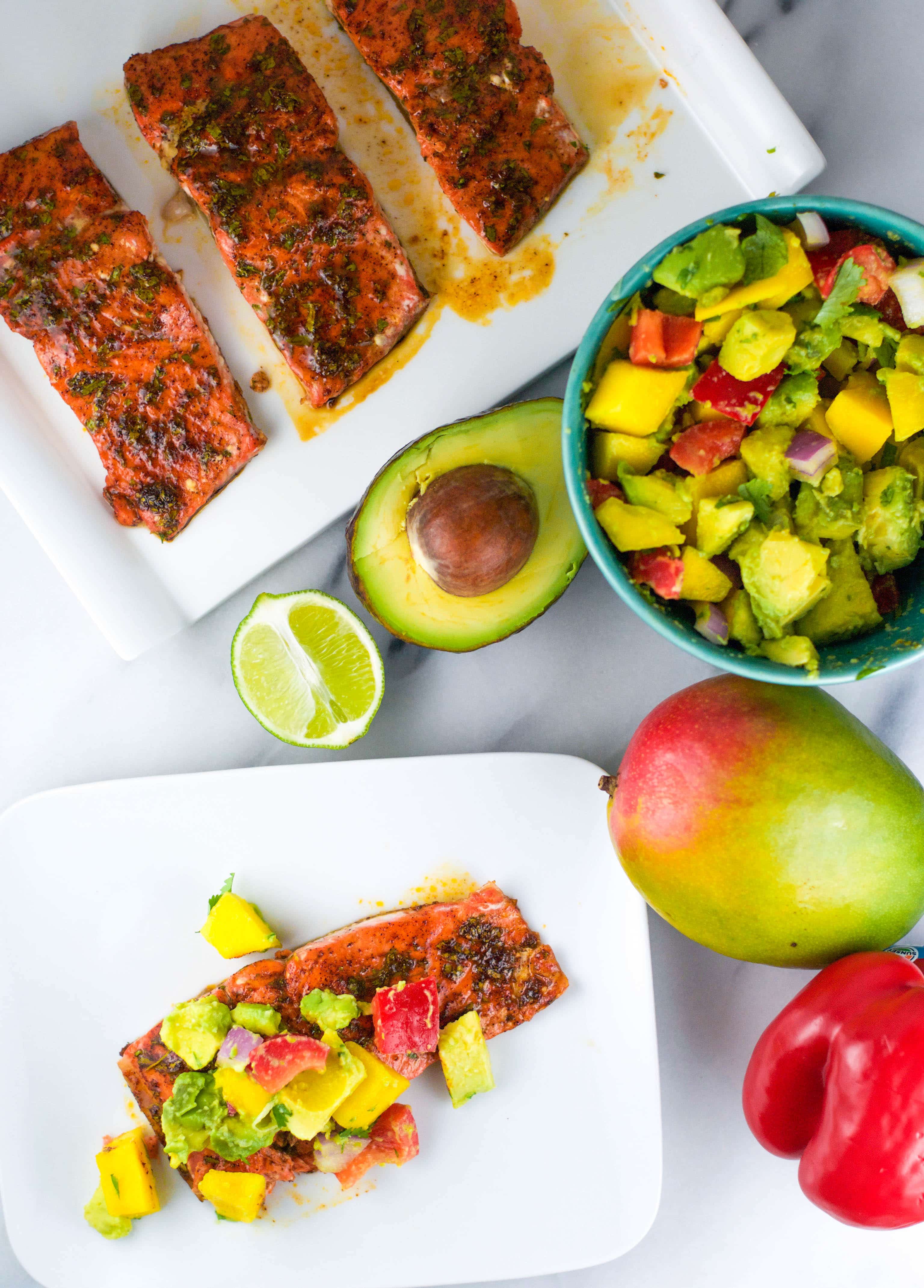 plate of salmon with mango avocado salsa on top with a bowl of salsa to the side.