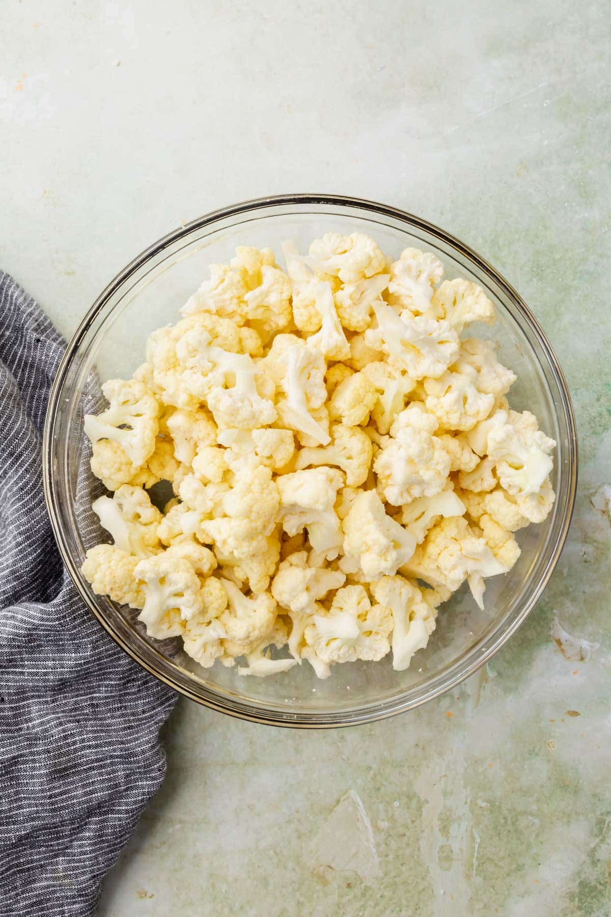 A glass mixing bowl with cauliflower florets in it.