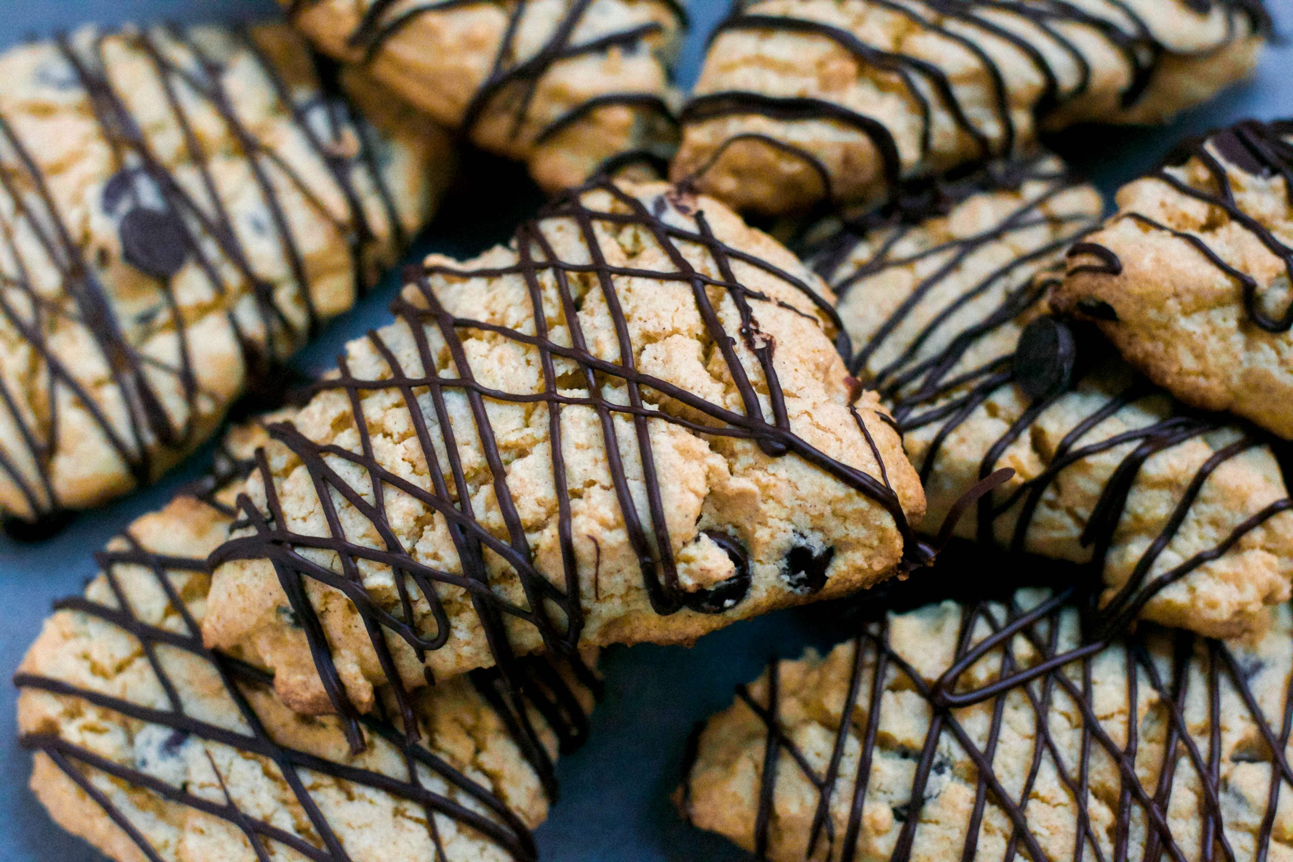 A pile of gluten-free chocolate chip scones with zig zag chocolate drizzles.