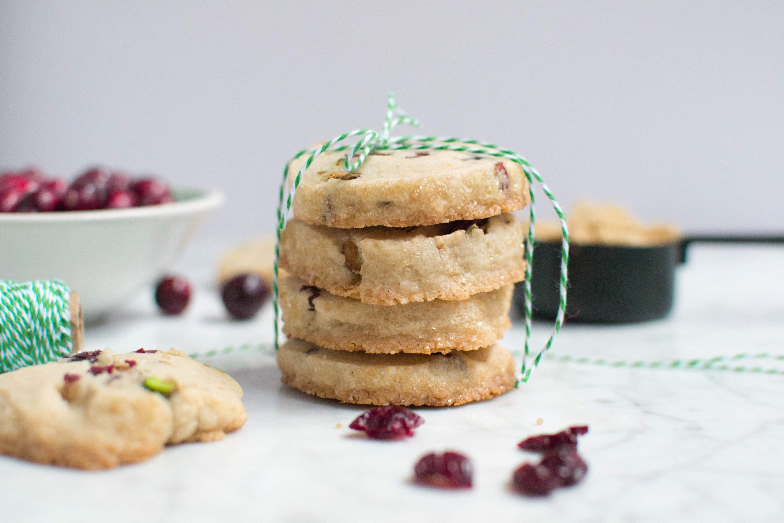 A stack of four pistachio cranberry shortbread cookies tied with green and white twine.