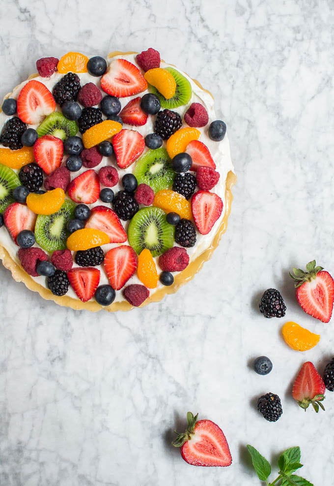 An aerial view of a gluten-free fruit tart topped with mandarin oranges, strawberries, blueberries, blackberries, raspberries, and kiwi.