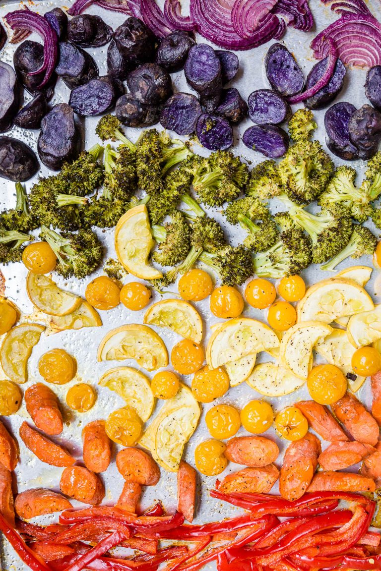 A sheet pan with rainbow vegetables roasted in the oven - bell peppers, carrots, squash, tomatoes, broccoli, potatoes and red onions.