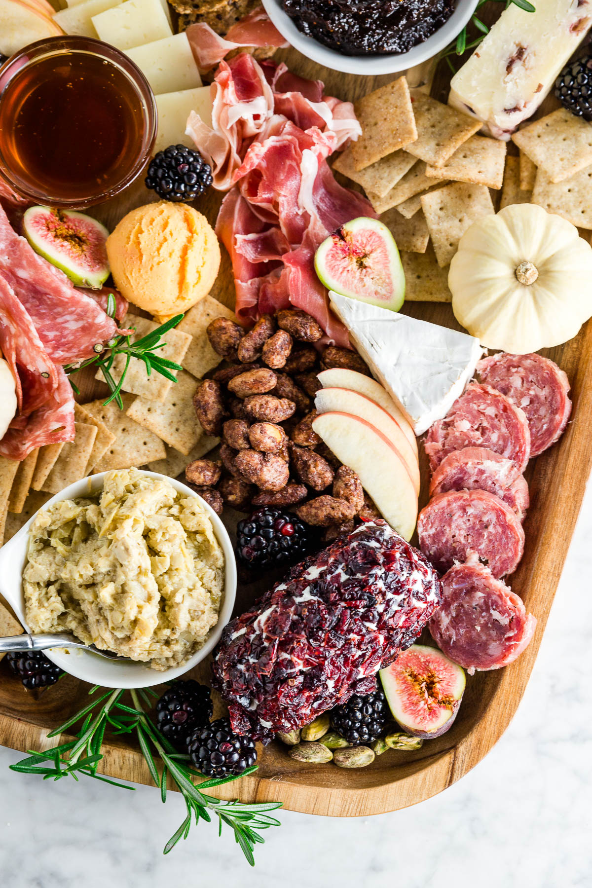 Cranberry goat cheese log, with artichoke dip, candied nuts, cheeses, cured nuts and crackers.