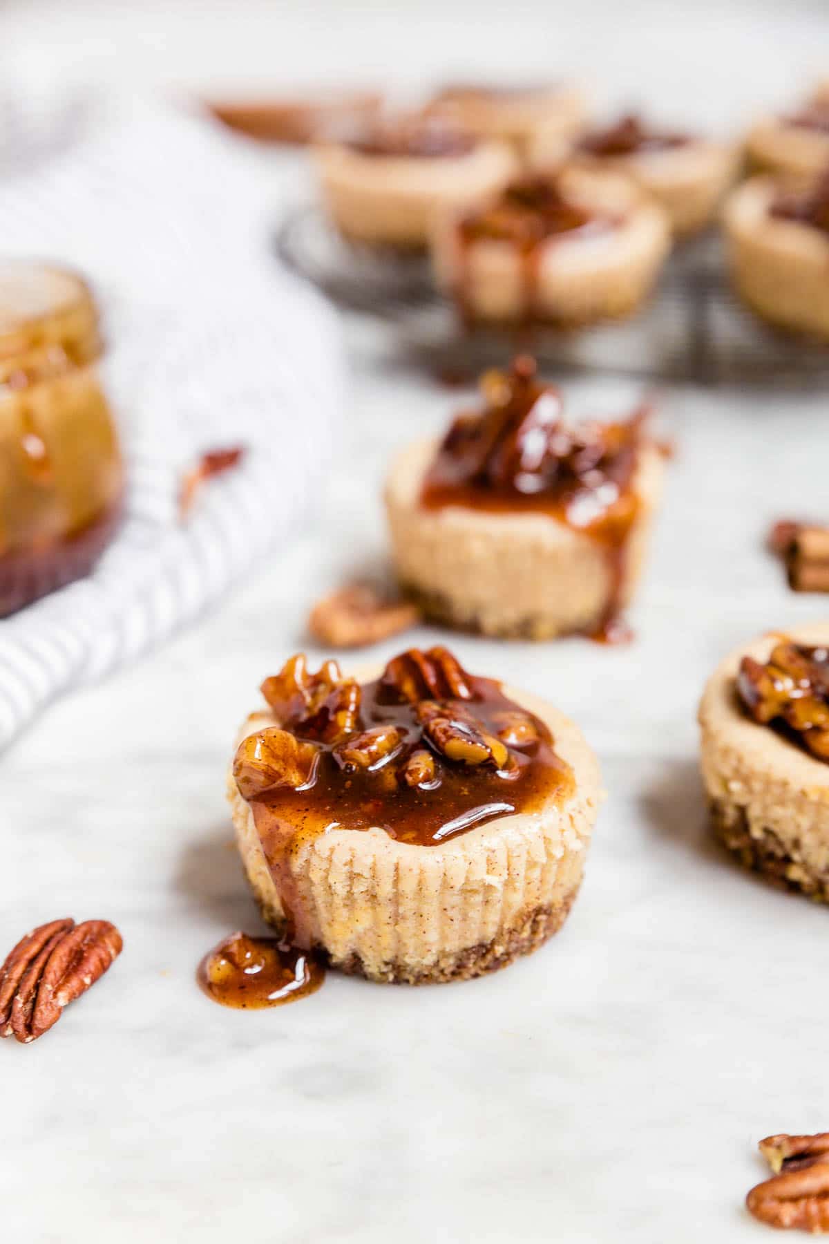 A mini pecan pie cheesecake with decadent caramel sauce with toasted pecans on top.