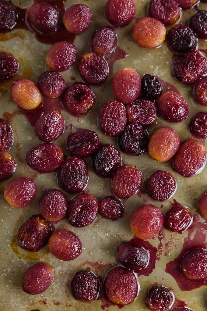 Roasted grapes on a baking sheet after being baked in the oven.