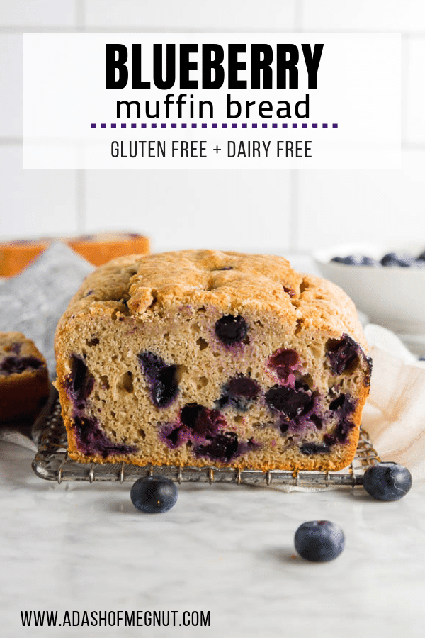 A loaf of gluten free blueberry muffin quick bread on a table with fresh blueberries.