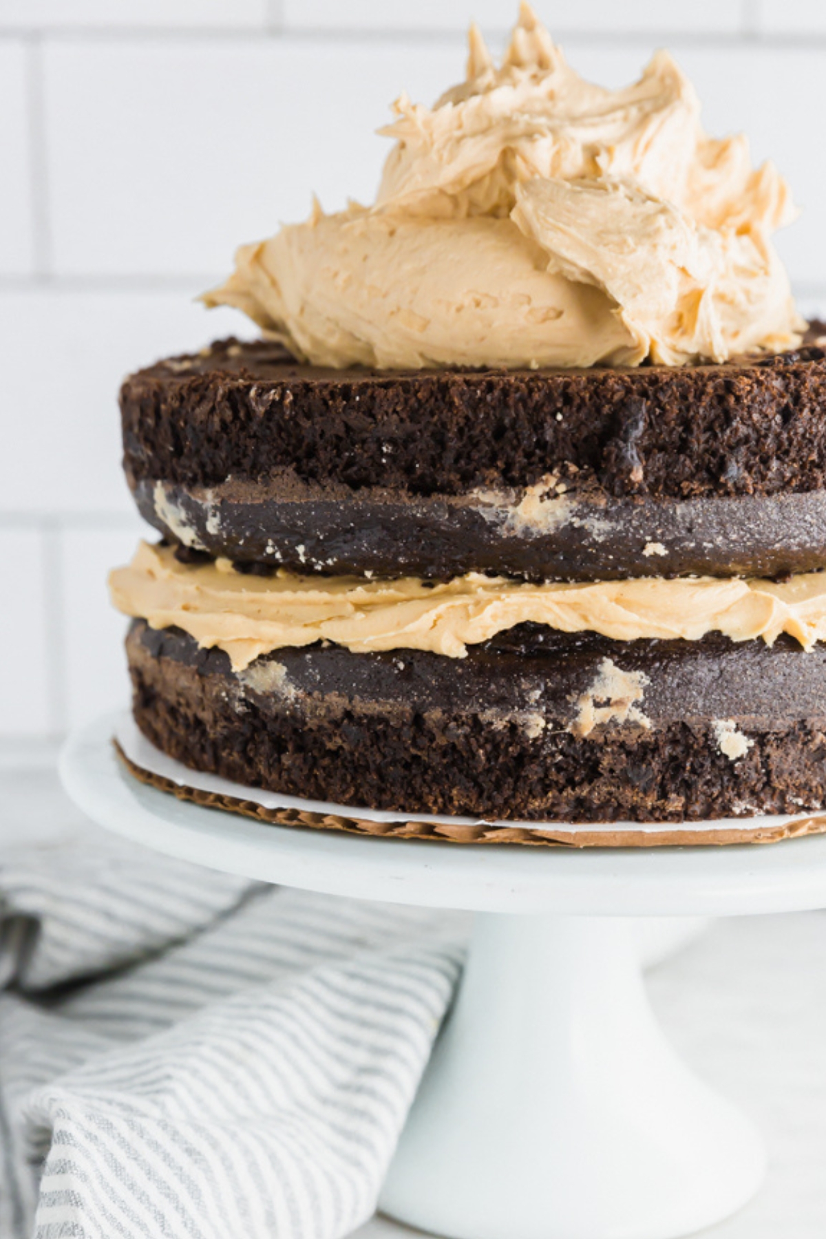 Unfrosted chocolate layer cake with large mound of peanut butter frosting on top.