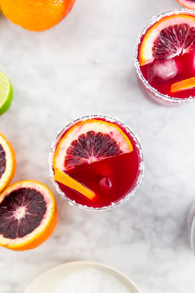 A aerial view of a blood orange margarita on the rocks with sliced blood oranges in it.