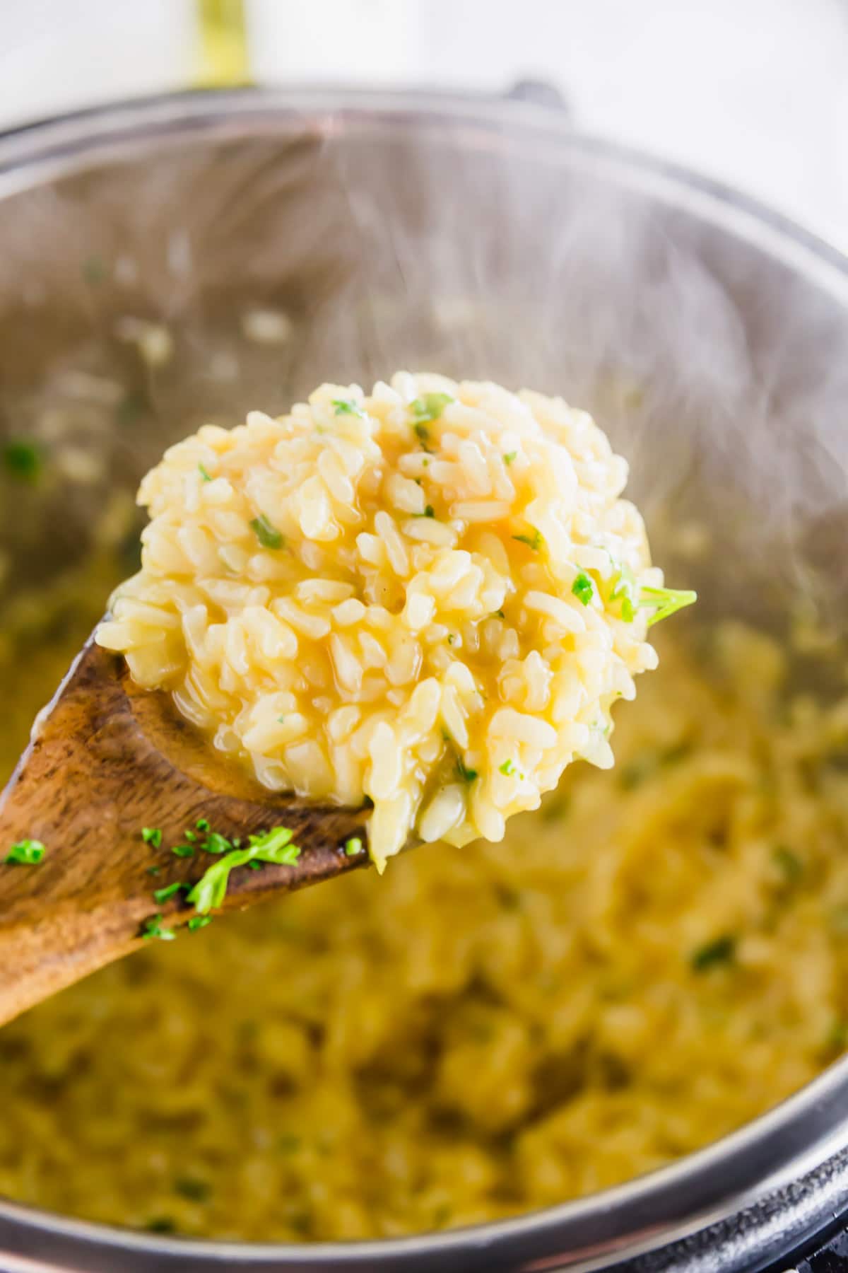 A photo of a spoon with a scoop of lemon risotto out of an instant pot.