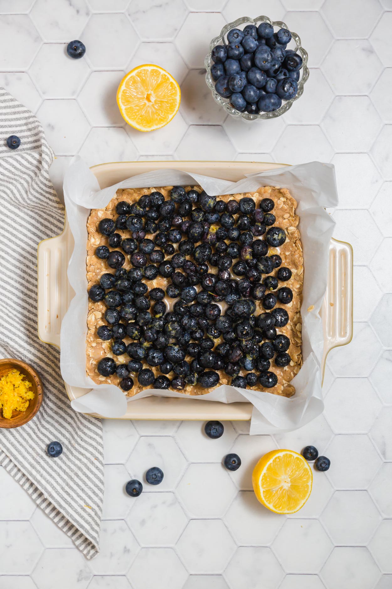 An overhead photo of blueberry filling over gluten-free crust in an 8x8-inch baking dish for blueberry pie bars.