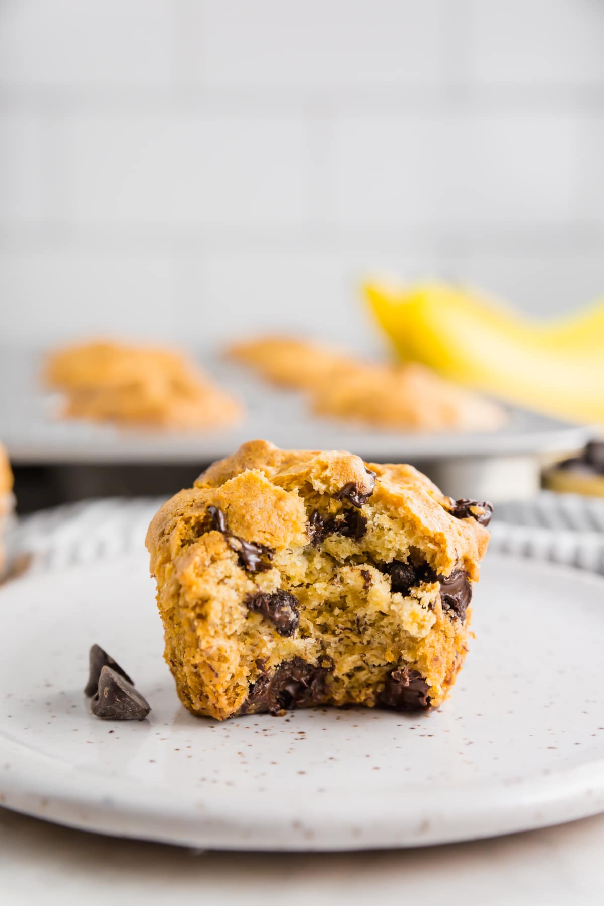 A photo of a gluten-free banana chocolate chip muffins with a large bite taken out of it.