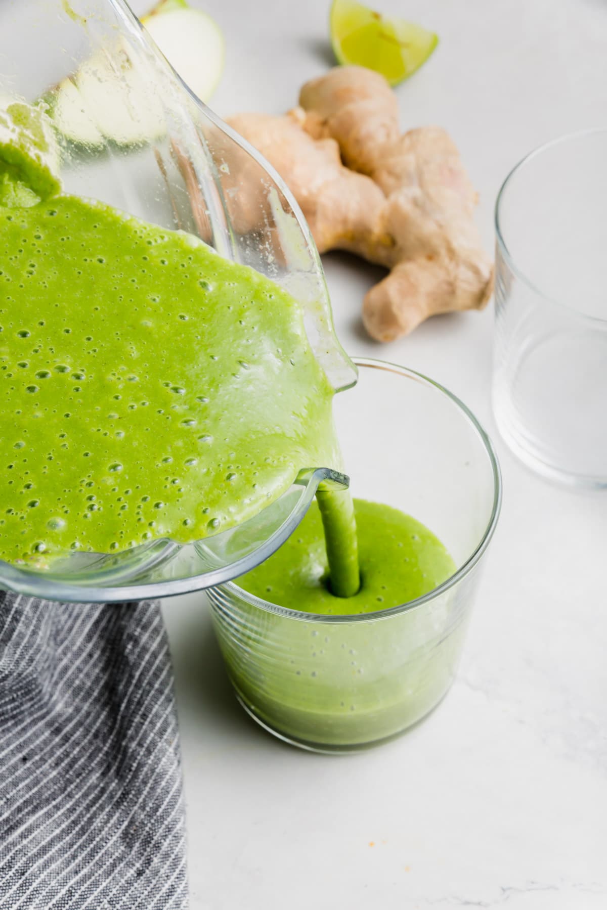 An apple kale green smoothie being poured into a glass.