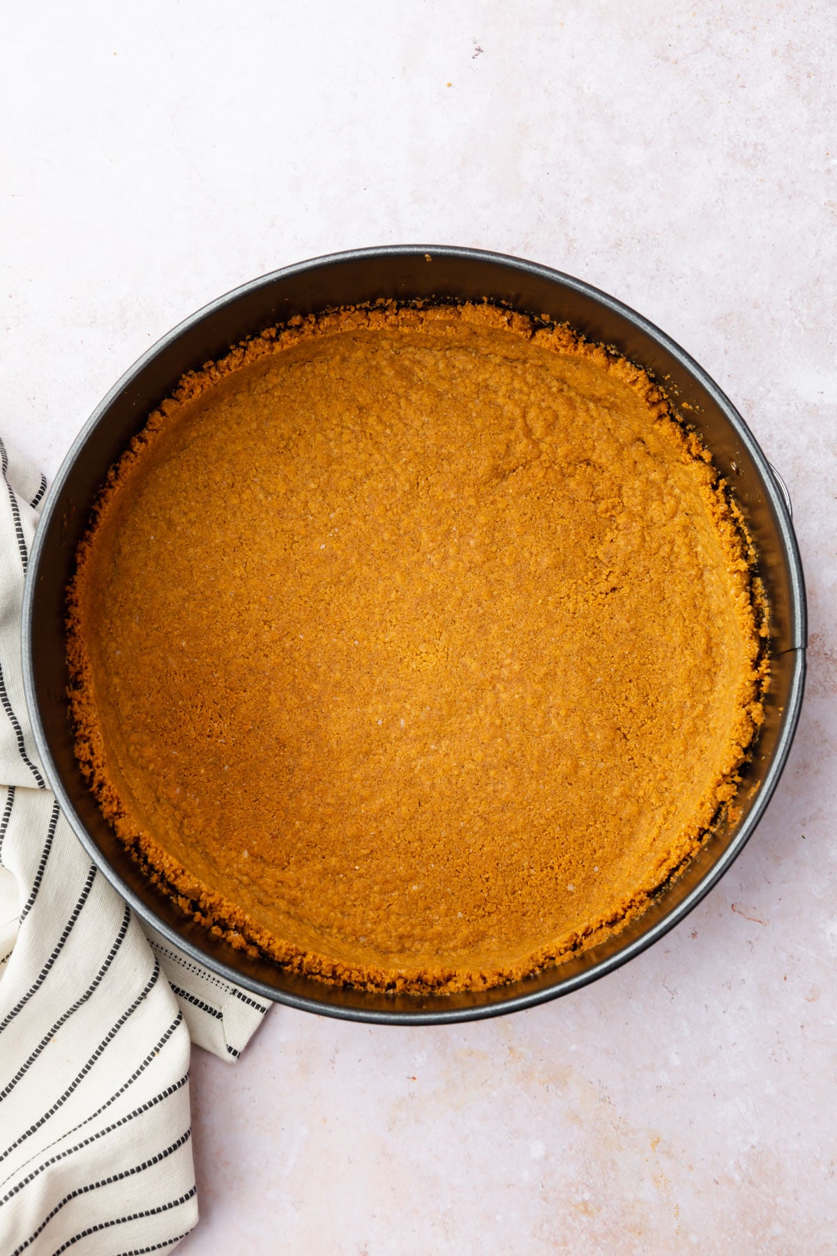 Baked gluten-free graham cracker crust in a springform pan.
