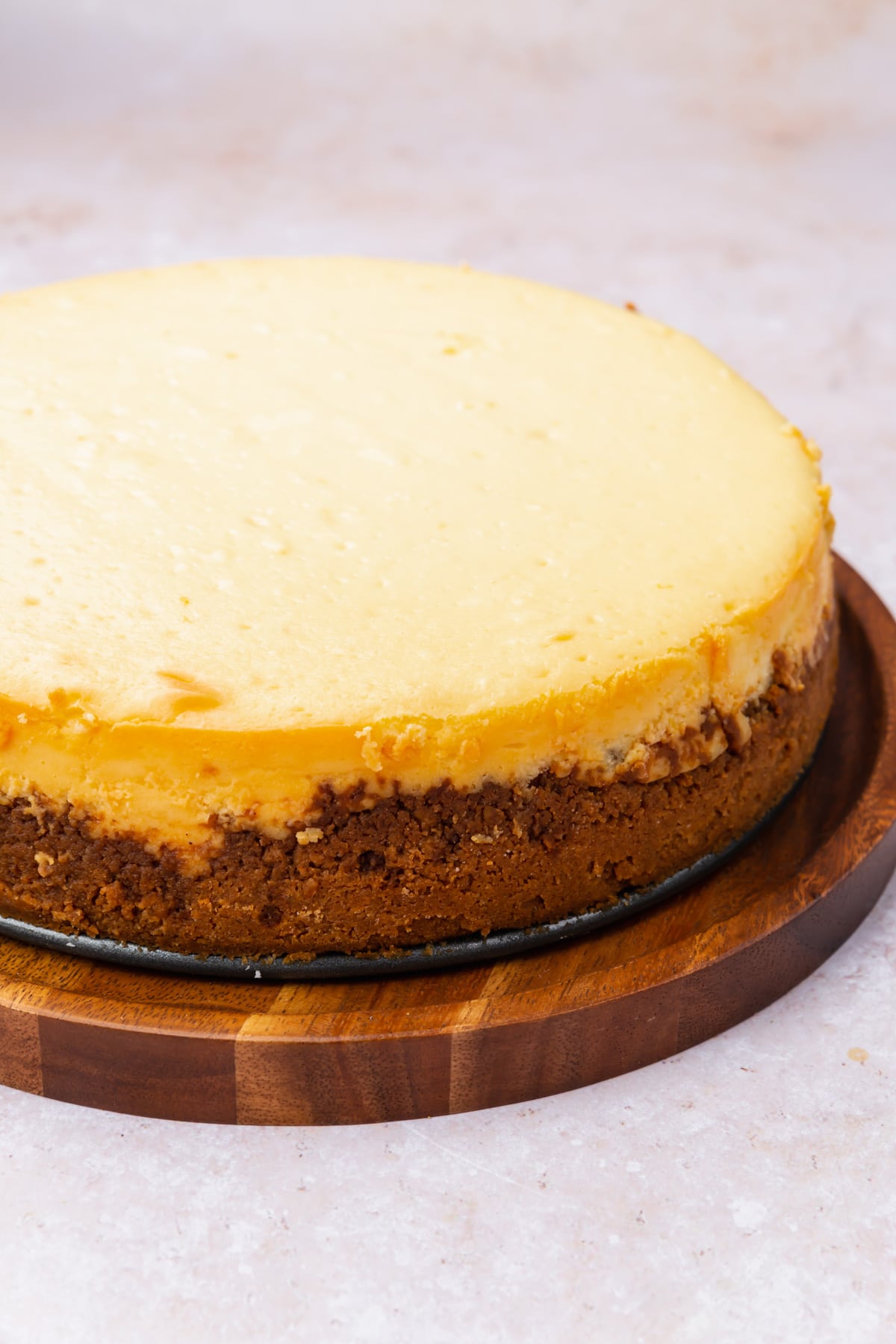 A plain gluten-free cheesecake on a wood board.