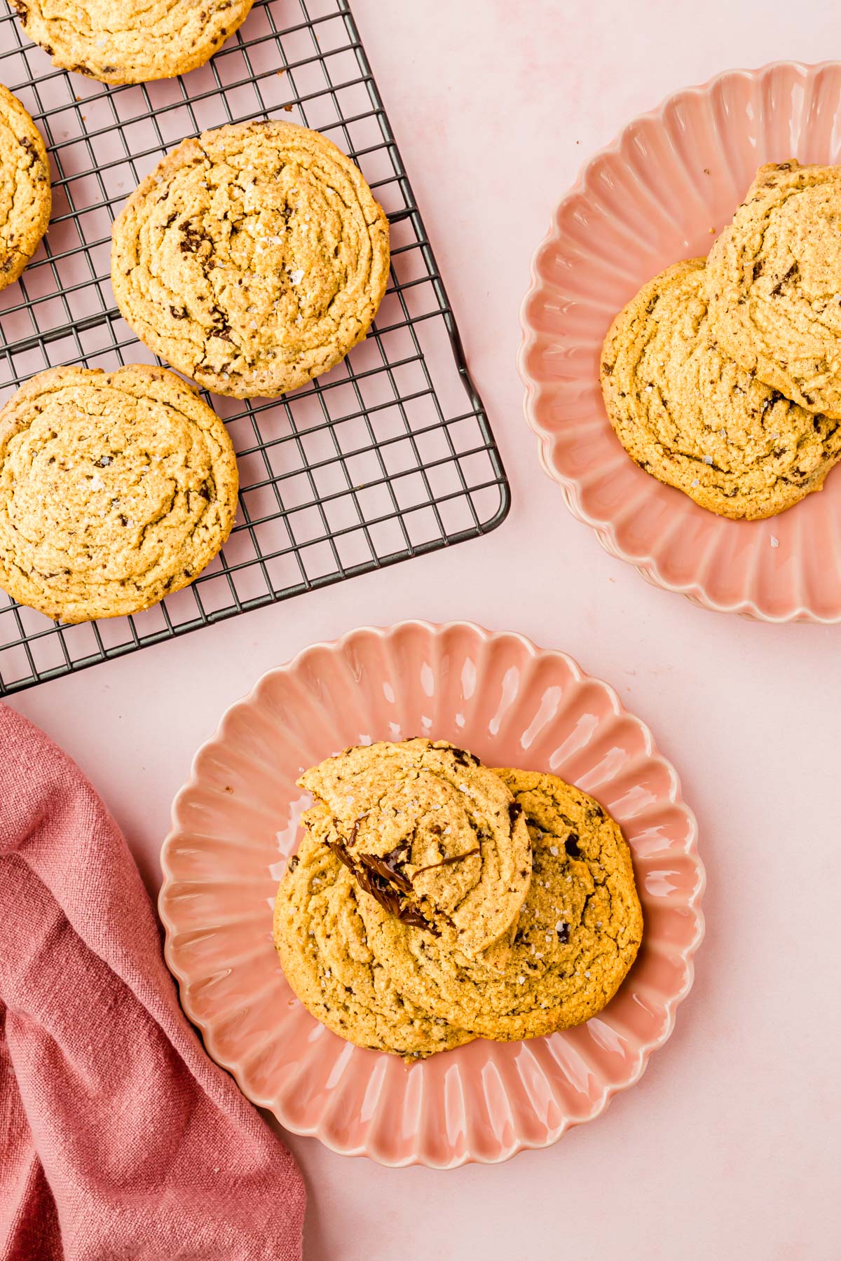 A couple of plates of gluten-free Nutella stuffed peanut butter cookies next to a cooling rack of more cookies.