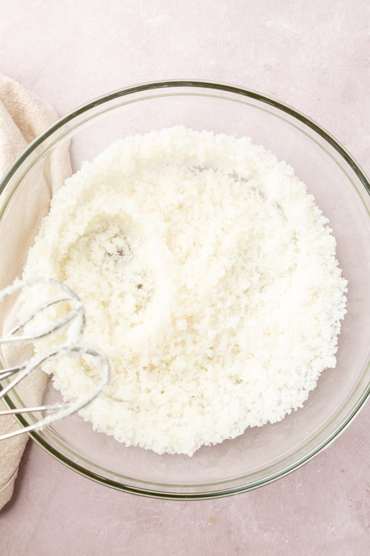 Oil and sugar being mixed in a glass mixing both with an electric mixer.