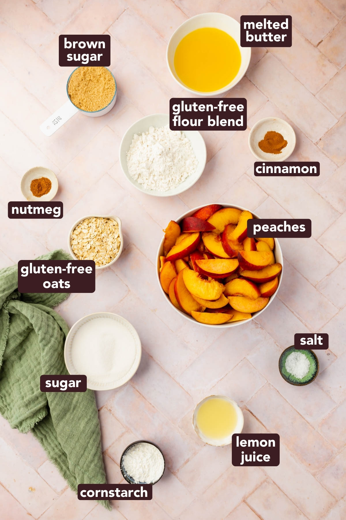 Top-down view of labeled ingredients for gluten-free peach crisp in bowls on a light surface, including brown sugar, melted butter, gluten-free flour blend, cinnamon, nutmeg, oats, sliced peaches, sugar, cornstarch, lemon juice, and salt.