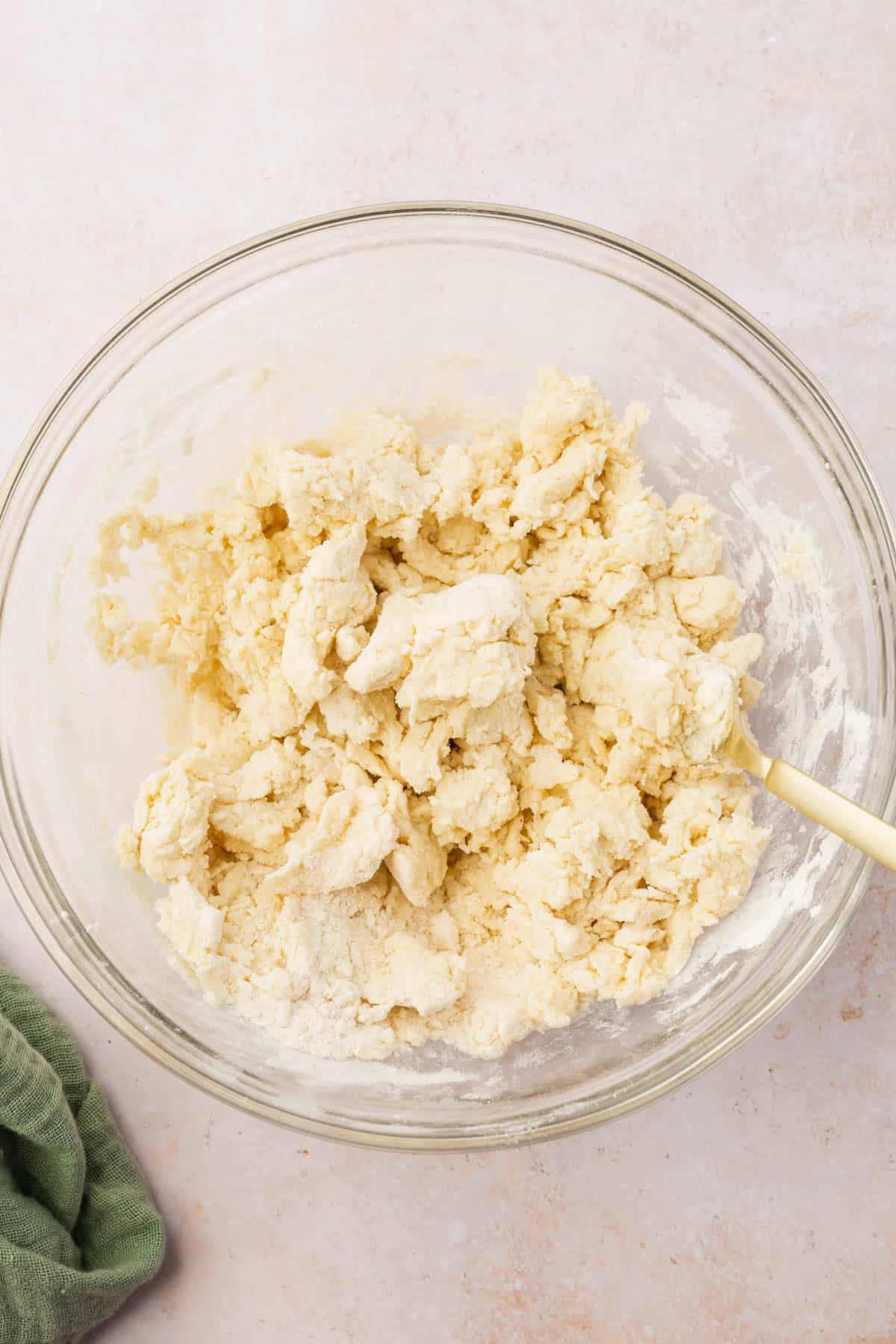 A scraggly gluten-free biscuit dough in a glass mixing bowl.