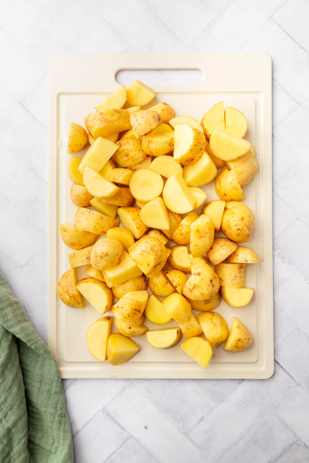 An overhead view of cubed Yukon gold potatoes on a cutting board.