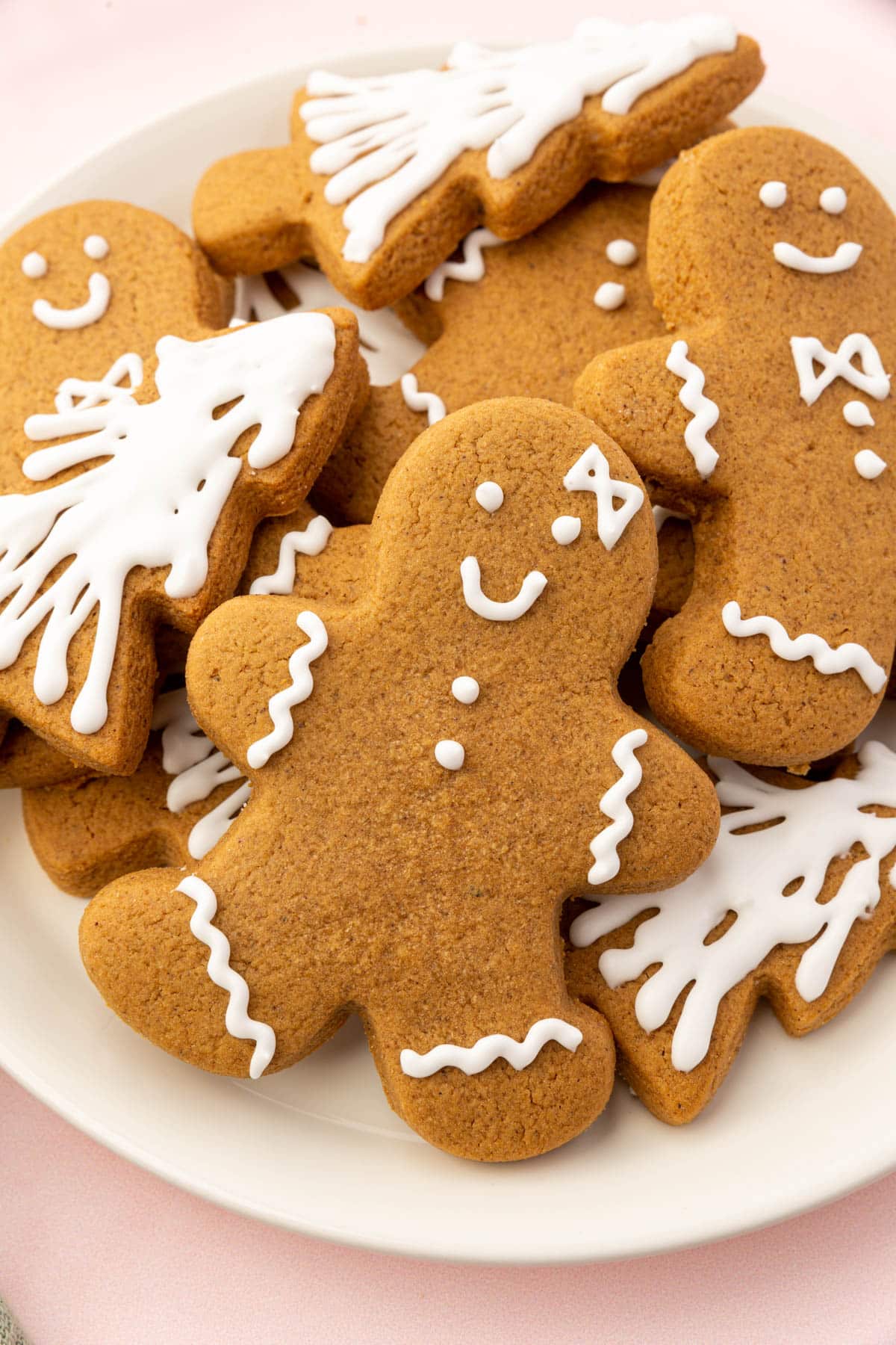 A plate of gluten-free gingerbread cookies shaped like Christmas trees and gingerbread men decorated with royal icing.