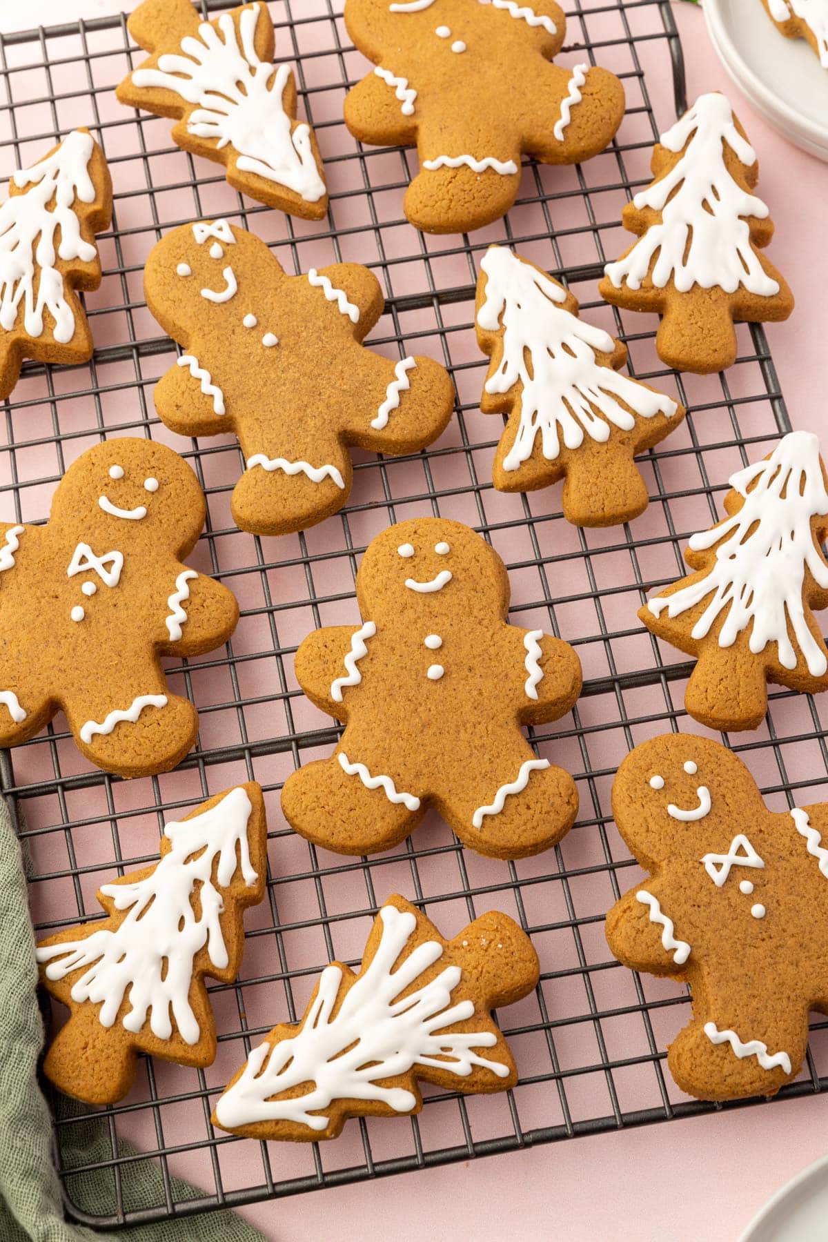 A cooling rack with gluten-free gingerbread men and gingerbread christmas tree cookies on it frosted with white royal icing.