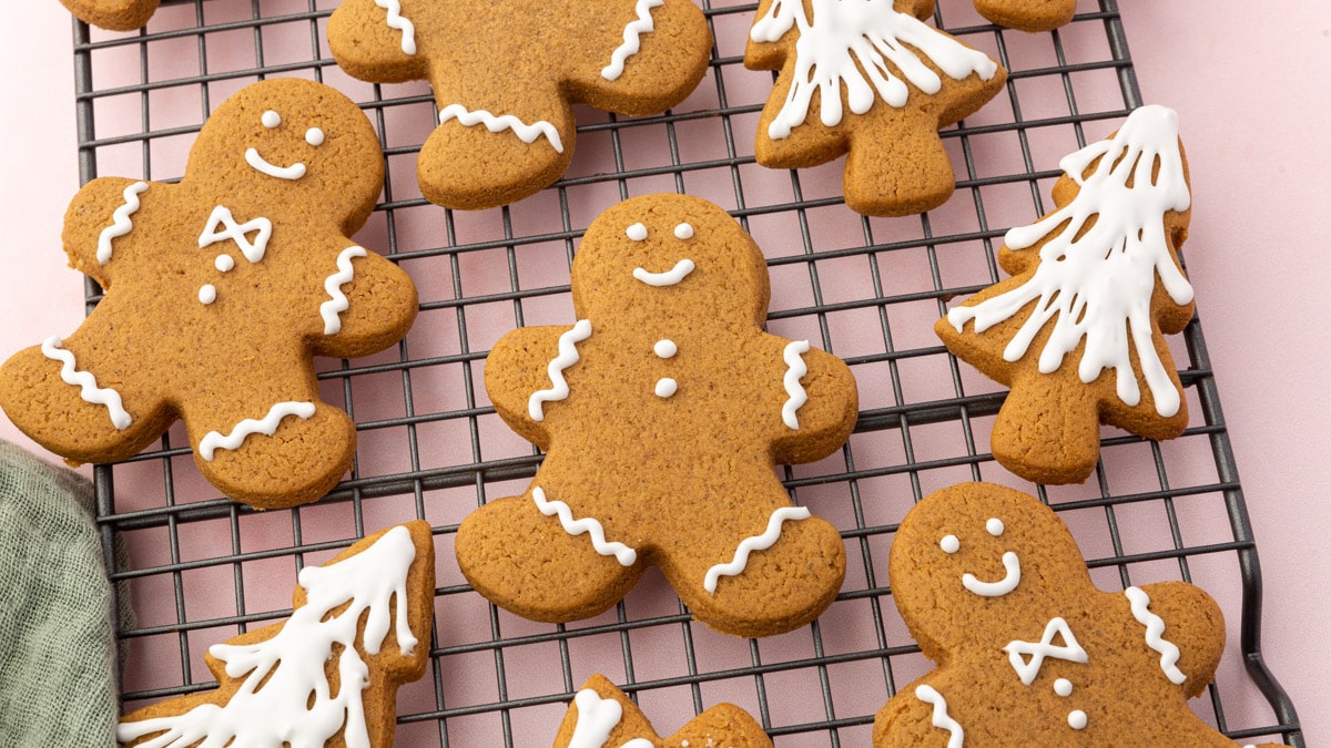 A cooling rack with gluten-free gingerbread men and gingerbread christmas tree cookies on it frosted with white royal icing.