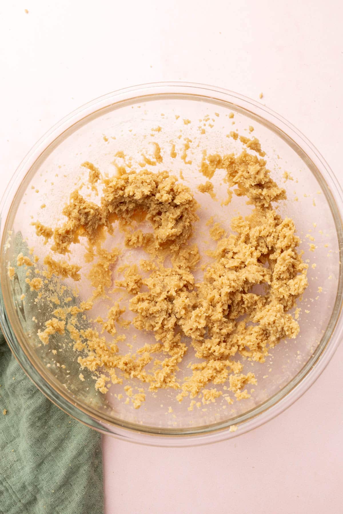 A glass mixing bowl with creamed butter and brown sugar in it.
