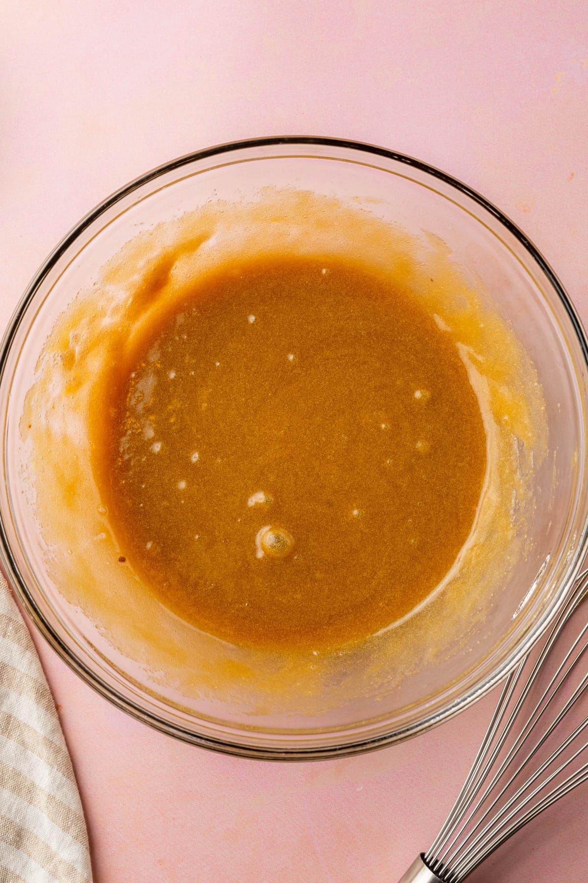 A glass mixing bowl filled with a brown sugar and melted butter mixture.