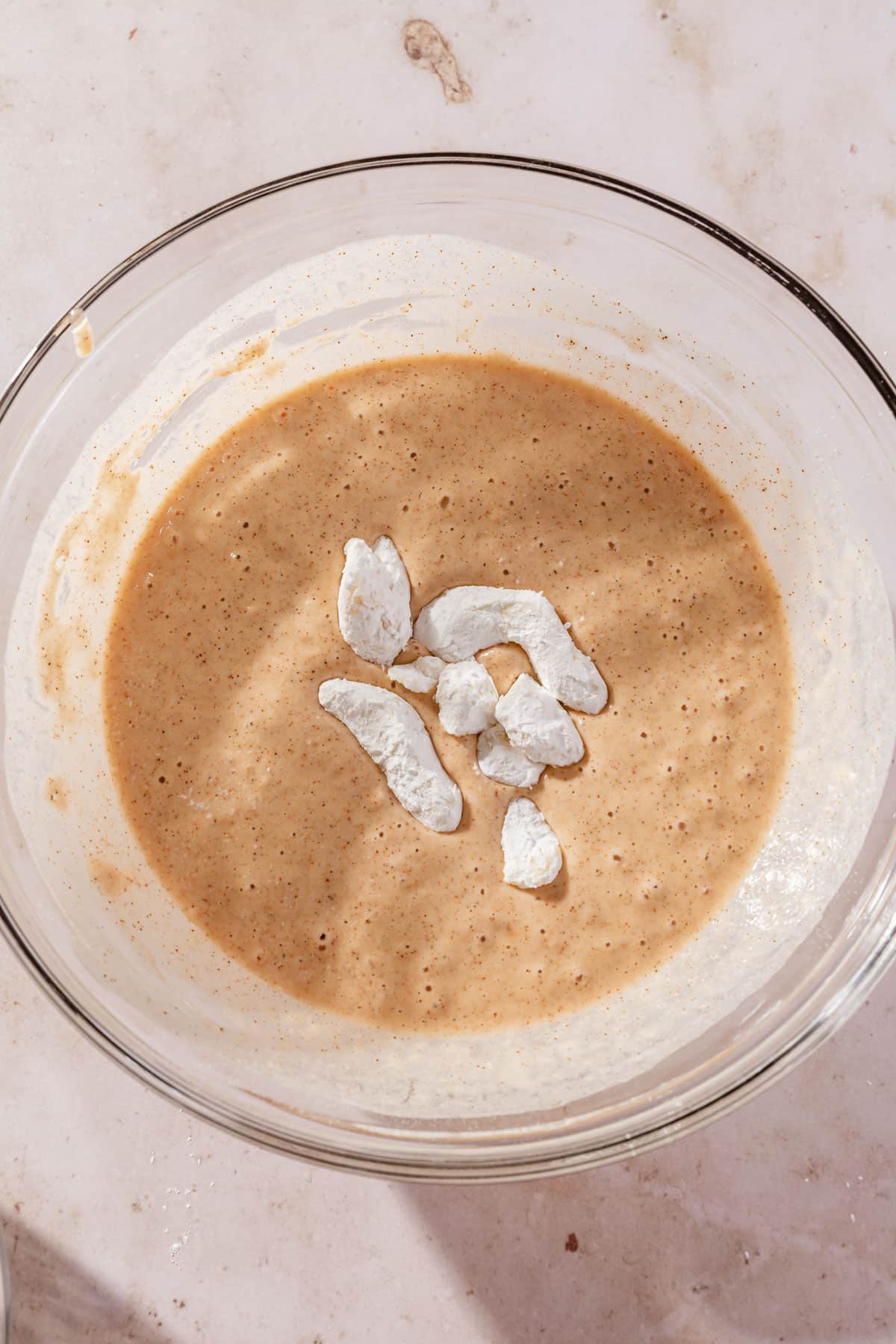 A handful of gluten-free cheese curds sitting in a bowl of gluten-free batter.