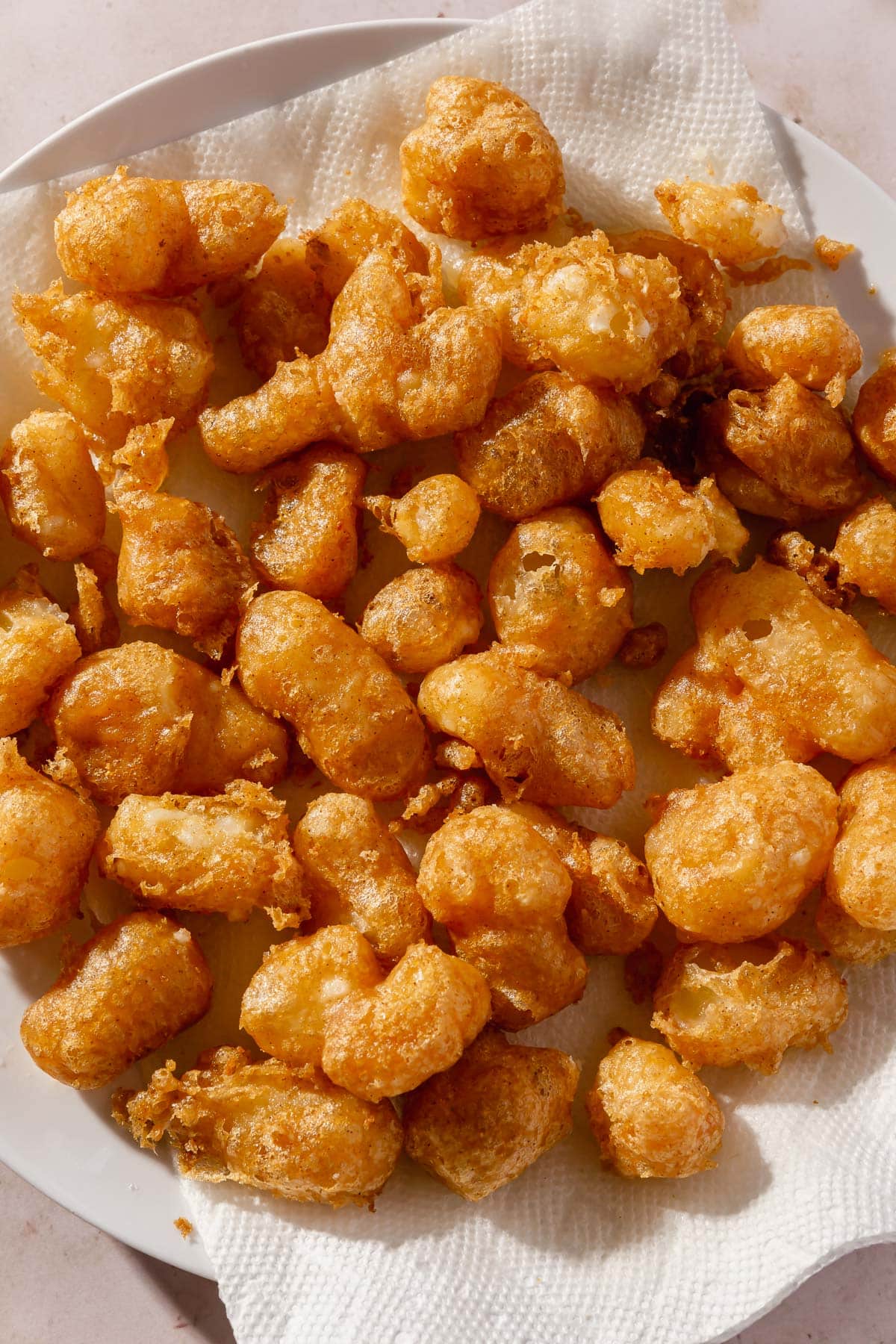 Fried gluten-free cheese curds on a plate lined with paper towels.