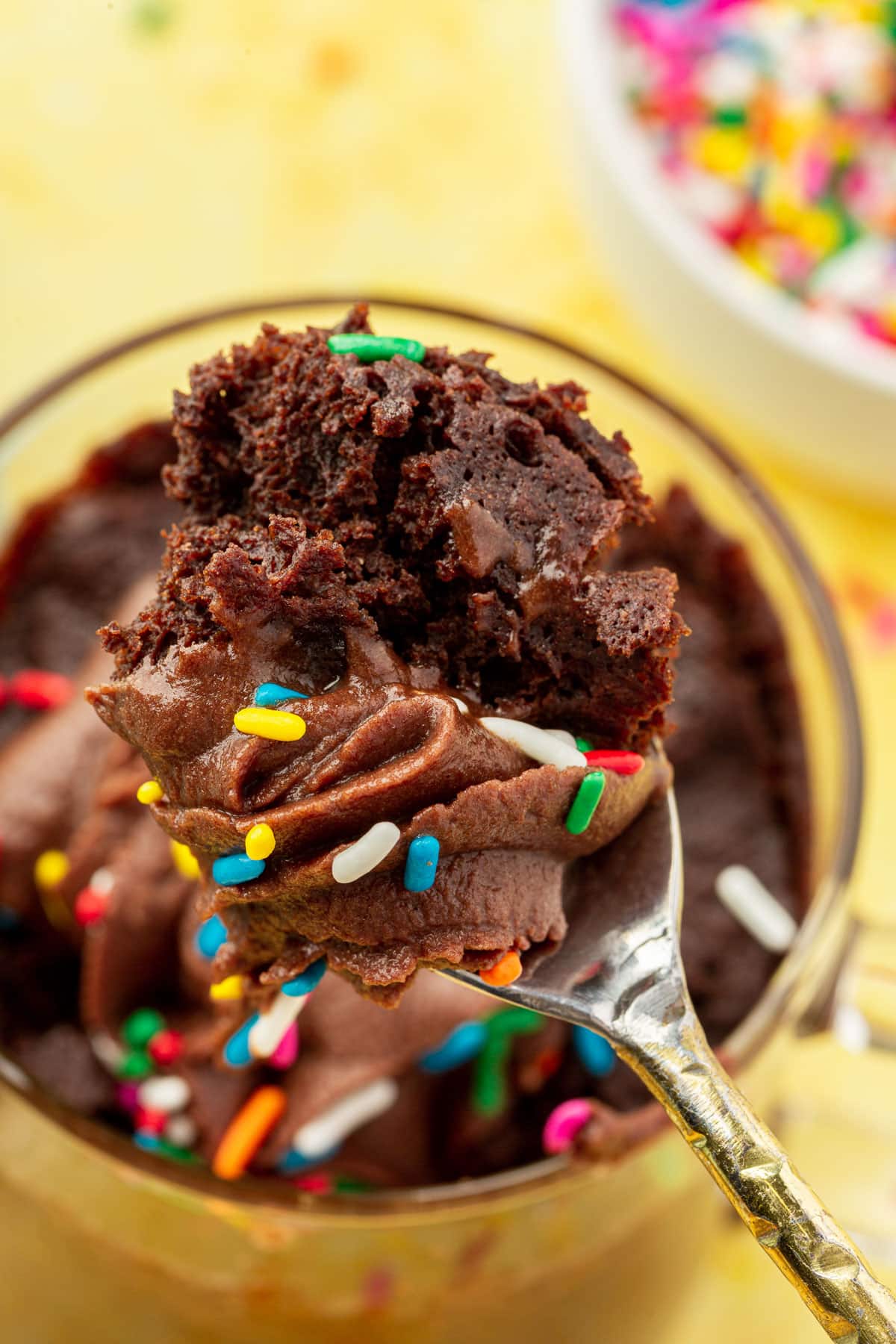 A spoonful of gluten-free chocolate mug cake over a mug of cake.