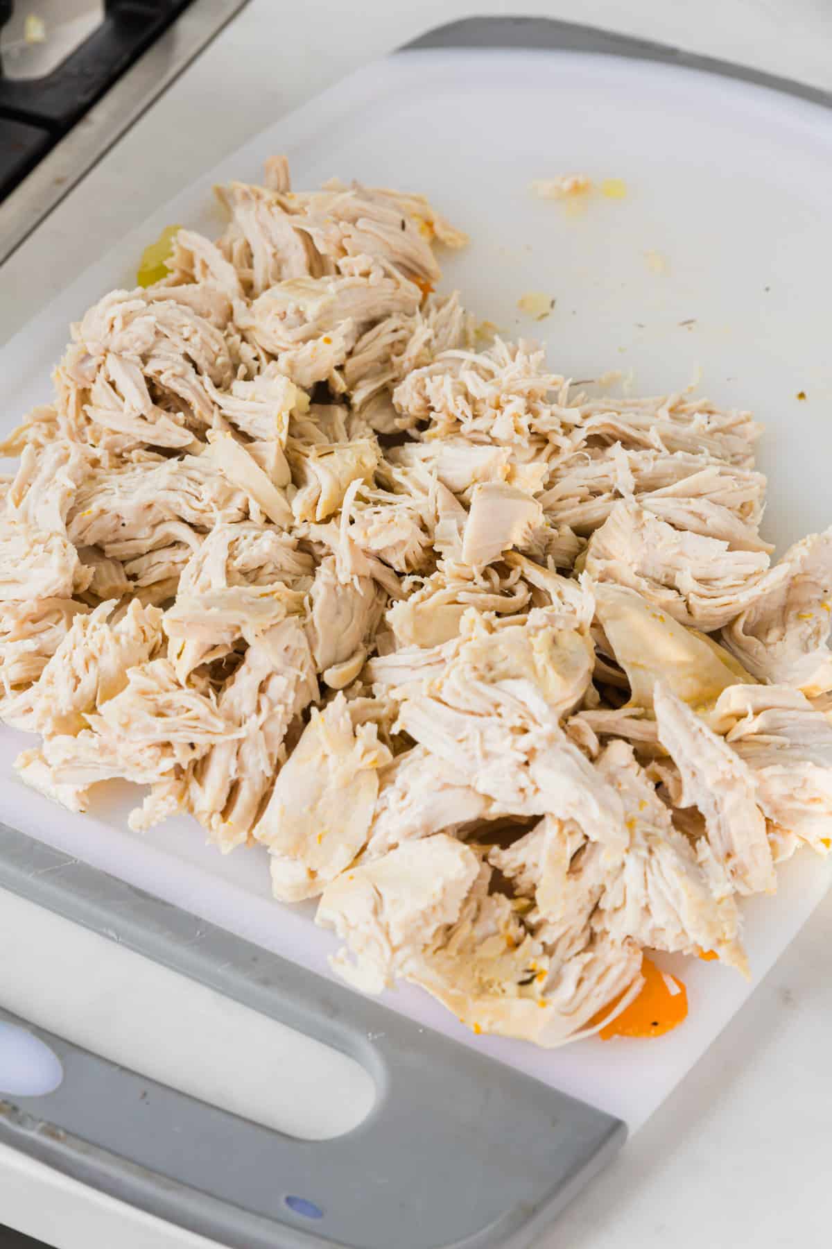 A cutting board with shredded chicken breast on it.