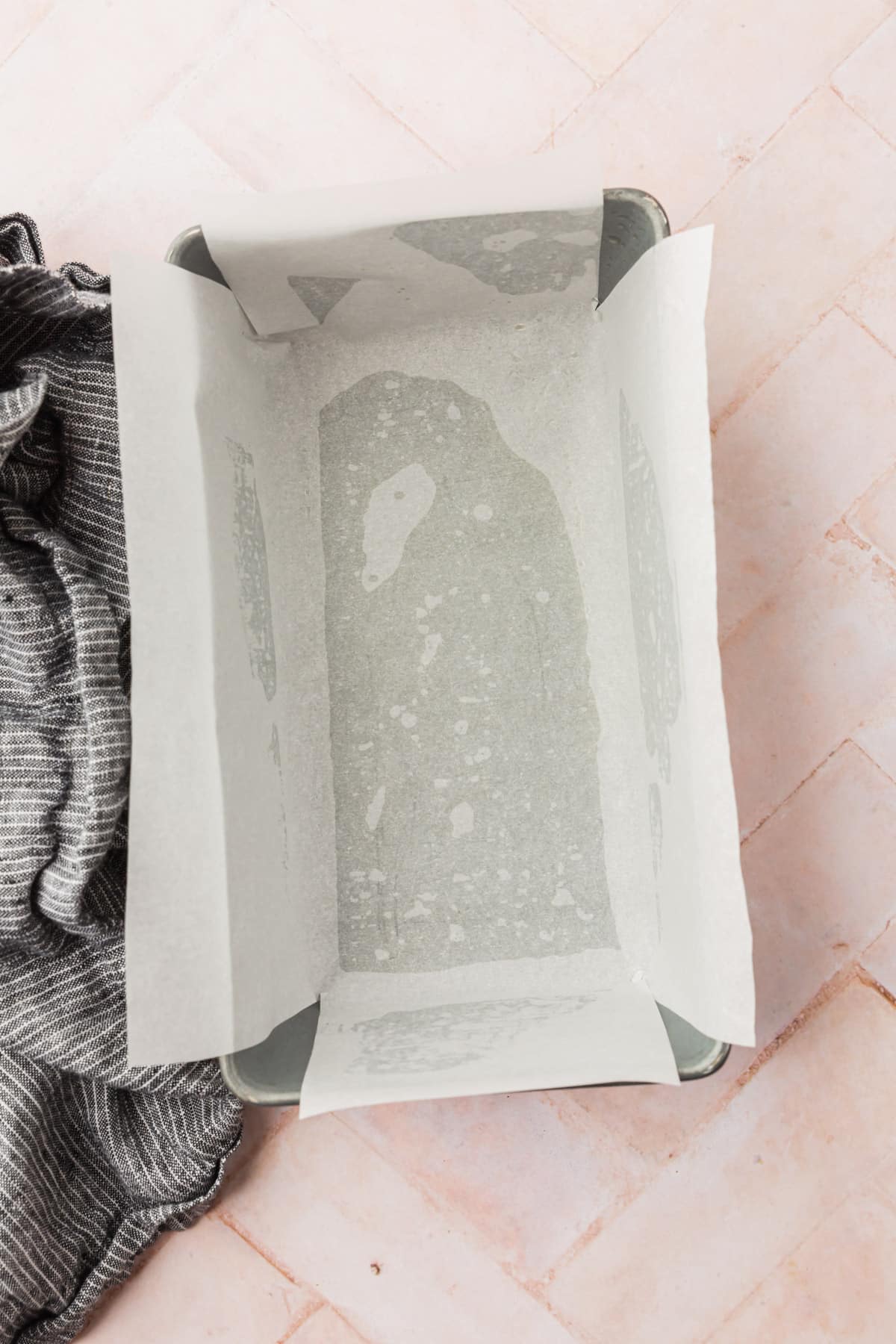 An overhead view of a loaf pan lined with parchment paper.
