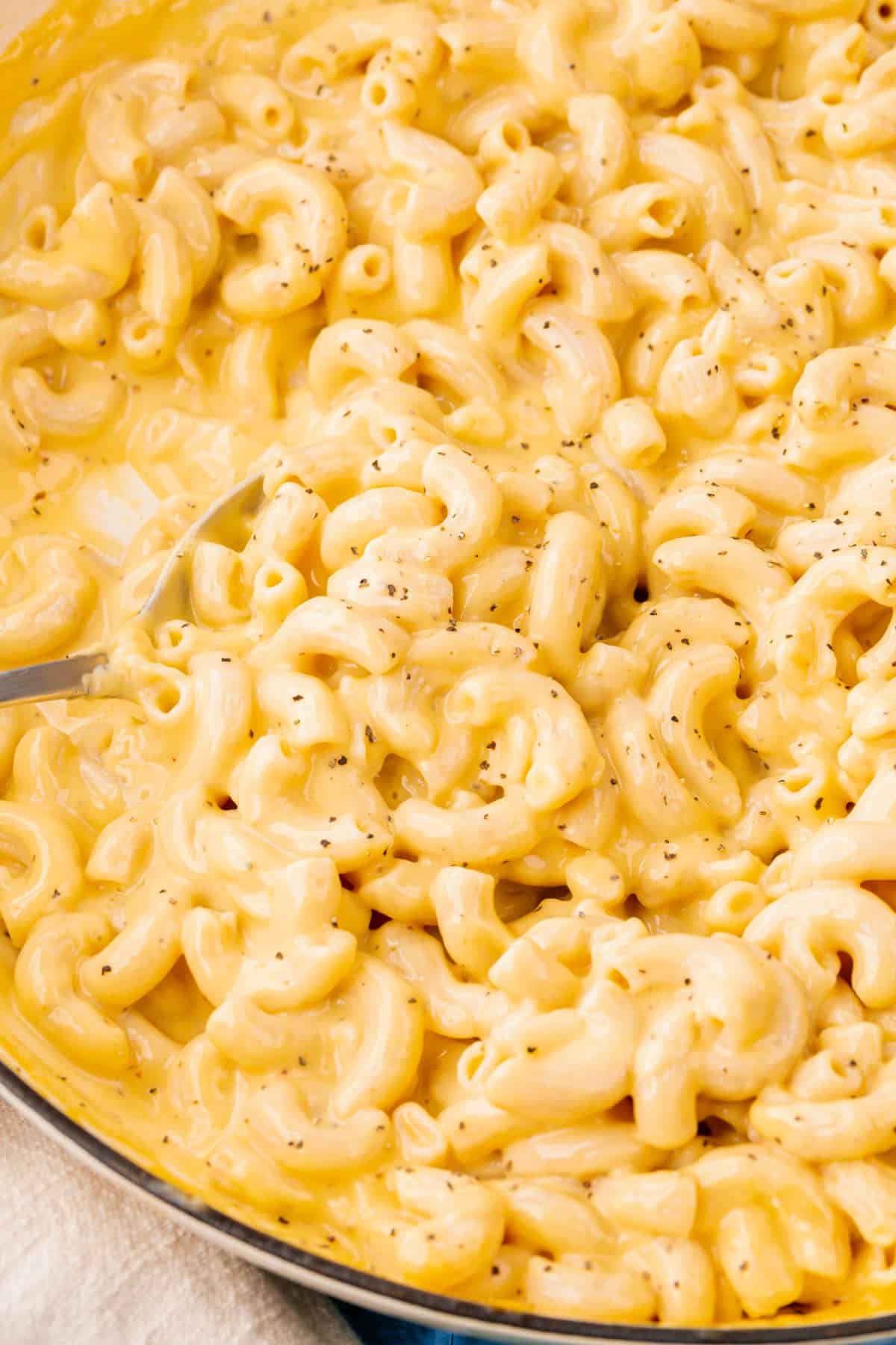 A closeup of a skillet of gluten free mac and cheese with a spoon.
