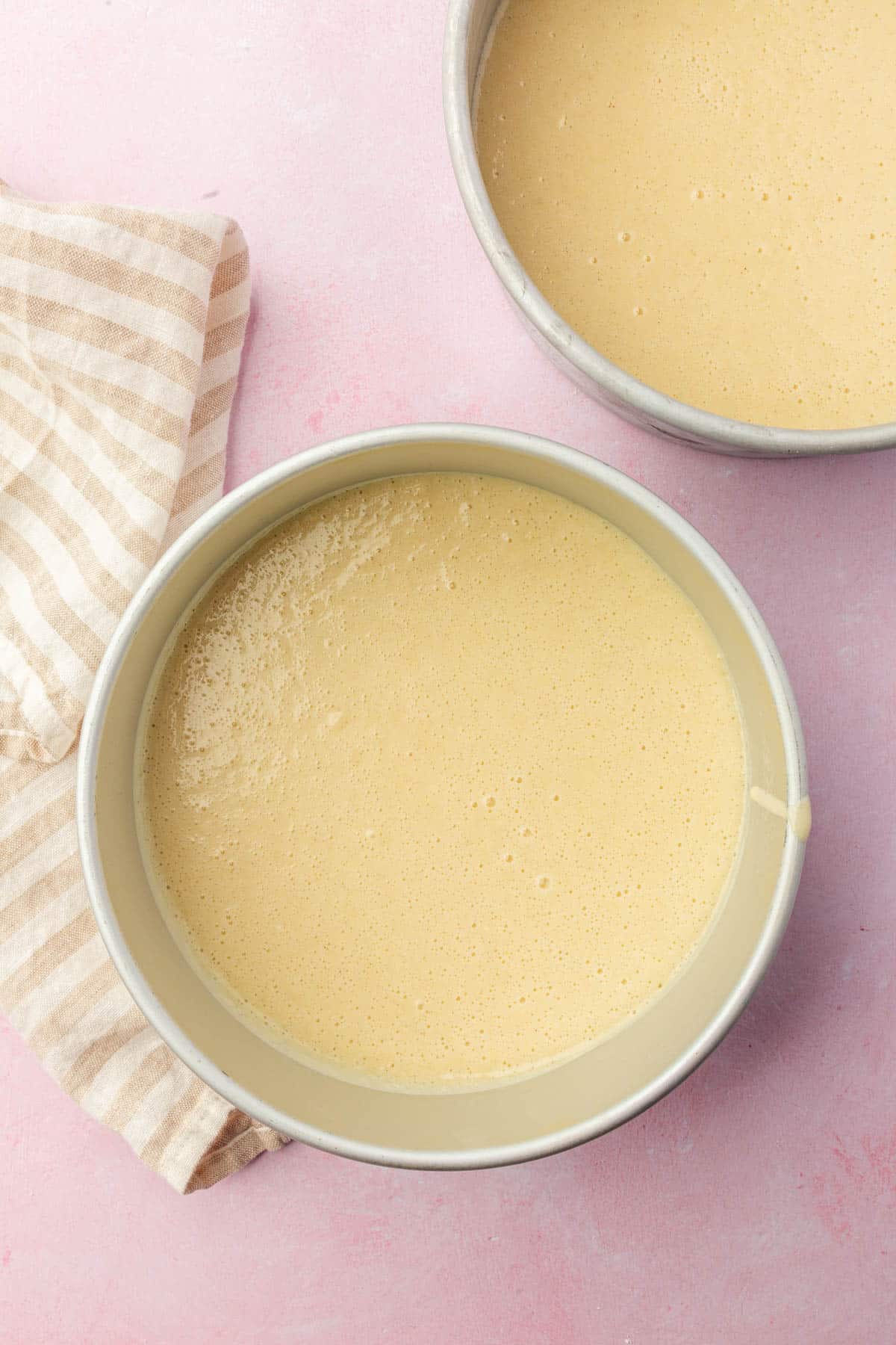 Two round 8-inch baking pans with gluten-free vanilla cake batter in them before baking in the oven.