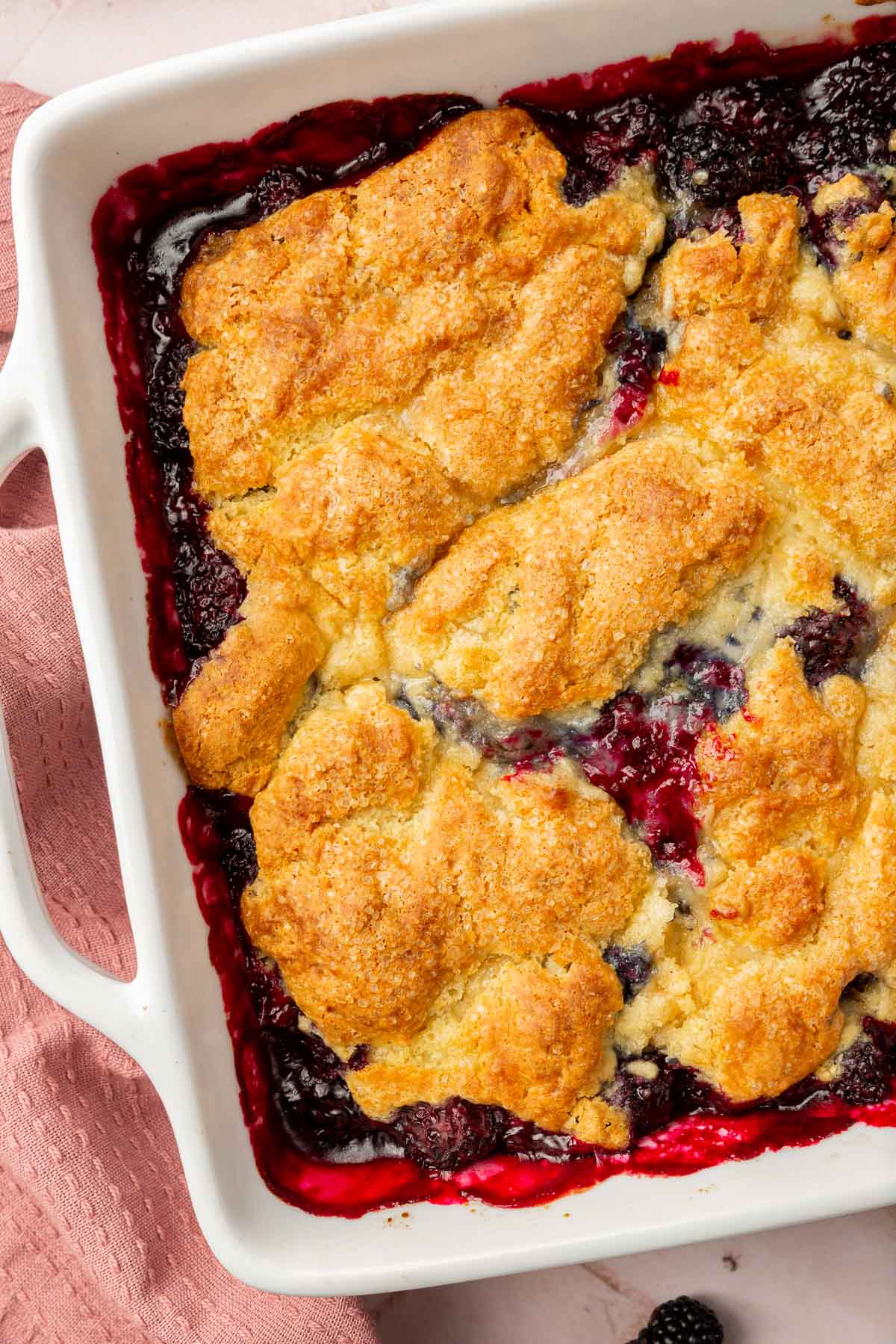 A close up of a square baking dish of a gf blackberry cobbler topped with turbinado sugar.